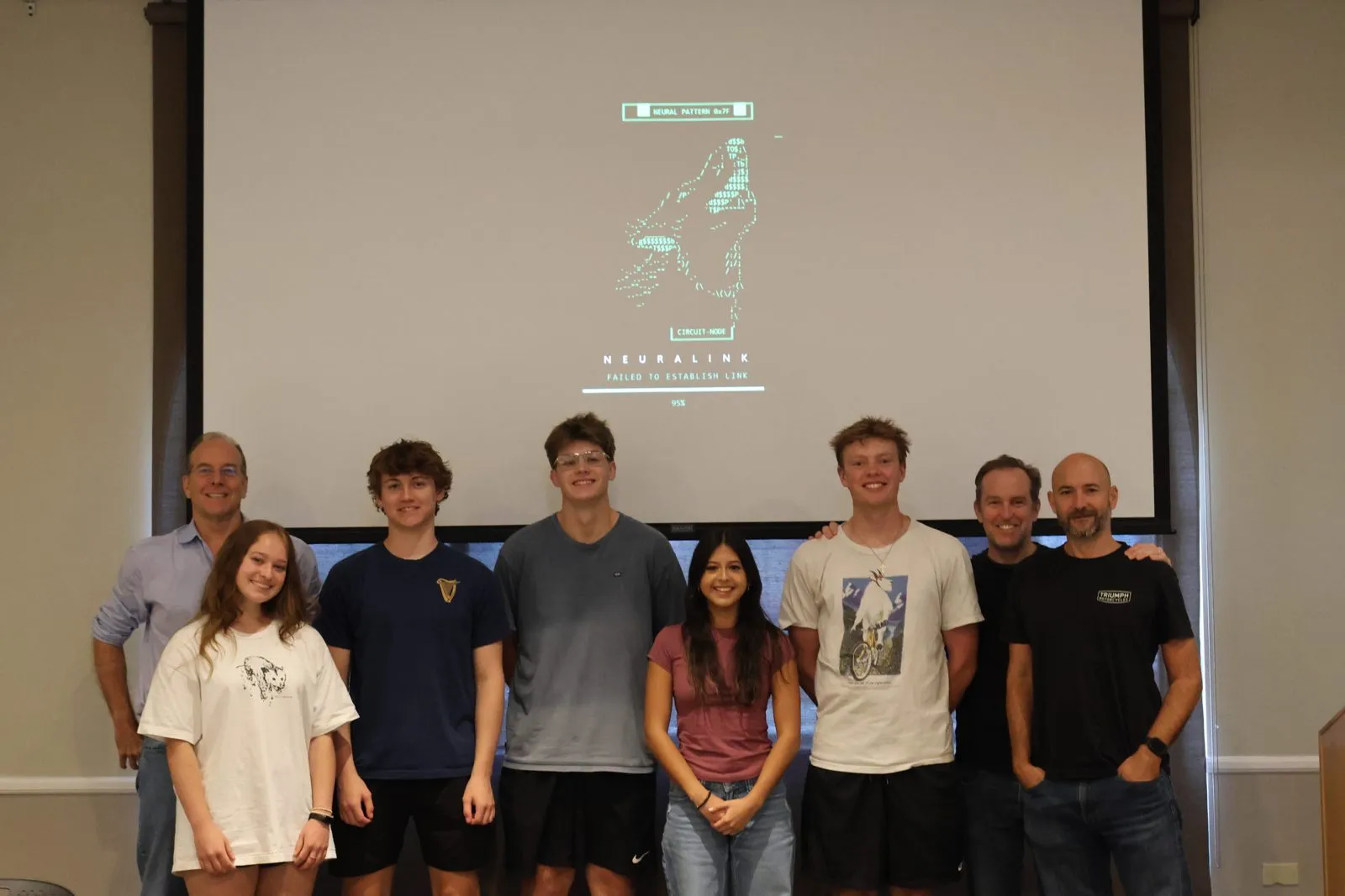 Participants and mentors pose together in front of a screen showing their graphic novel.